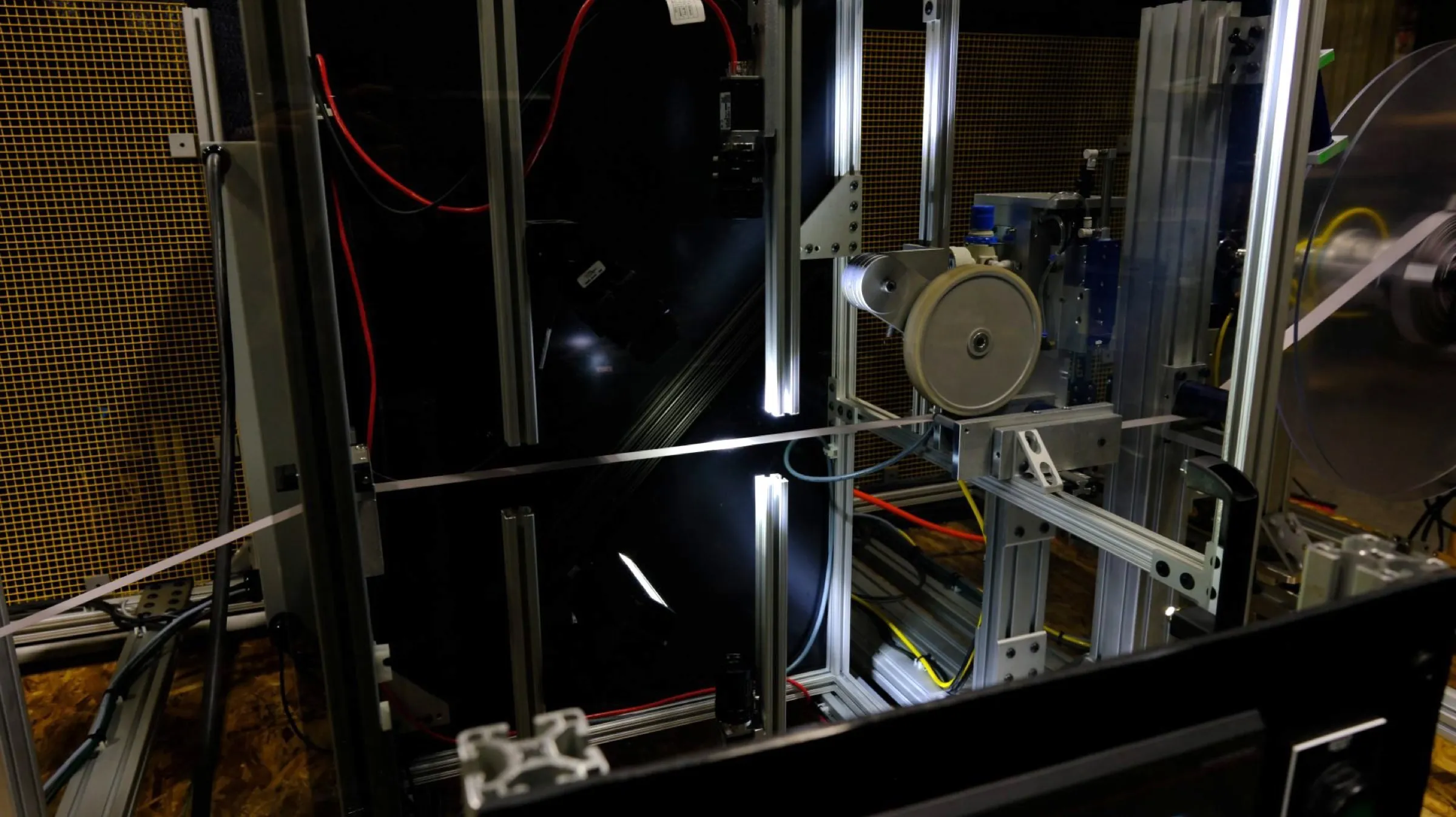 Inside the Shelfmark inspection unit: a strip of webbing running horizontally through the frame between backlit inspection bars, with the cameras aimed at it from behind the glass.