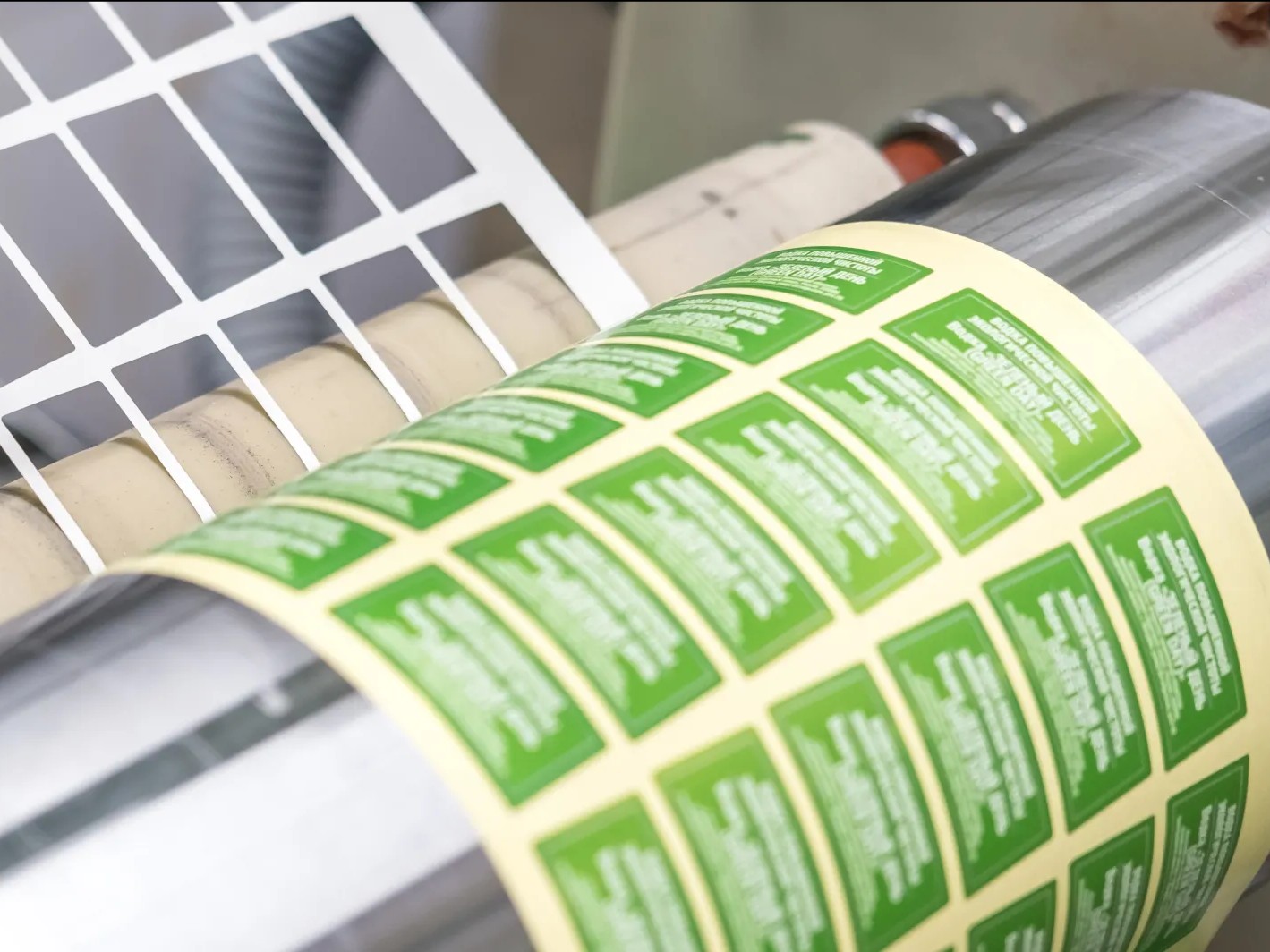 A printed label web running through a die-cut station on a label press